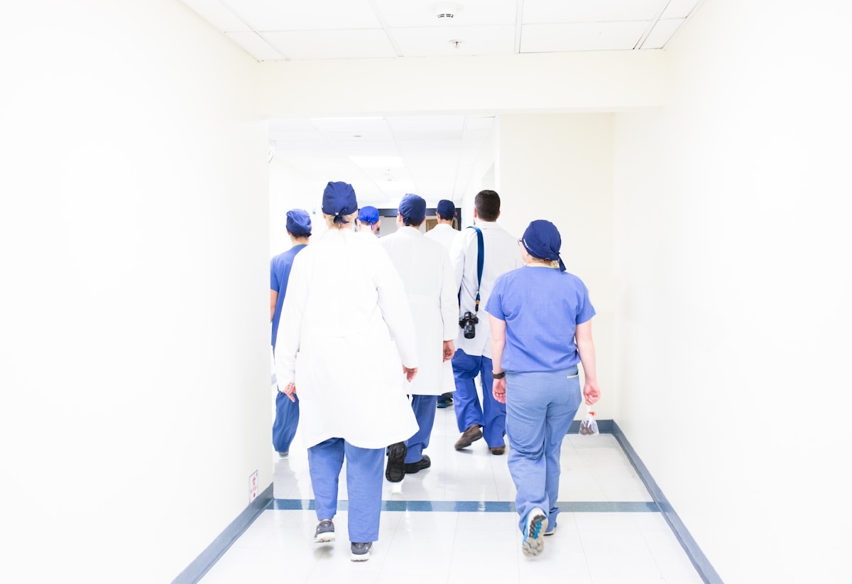 A medical team in scrubs and white coats walking along a hospital corridor