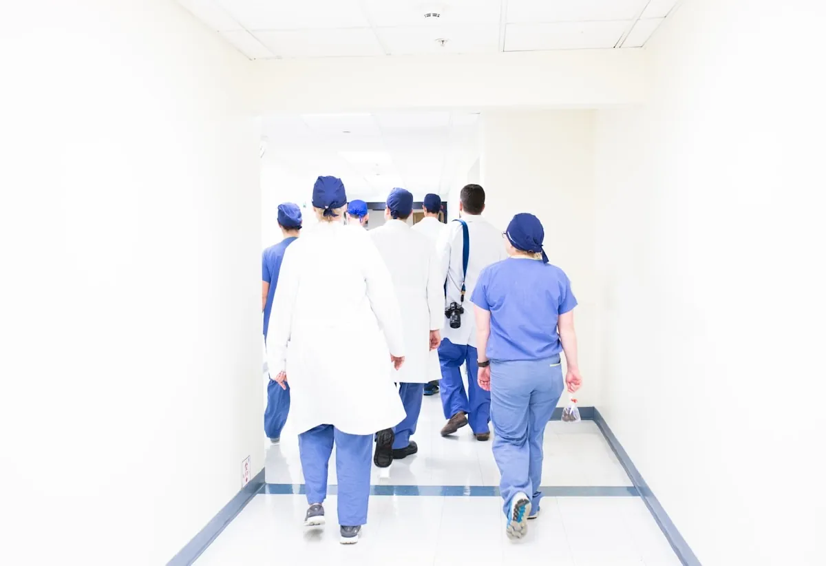 A medical team in scrubs and white coats walking along a hospital corridor